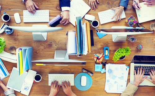 view from above a desk showing four people working and their equipment