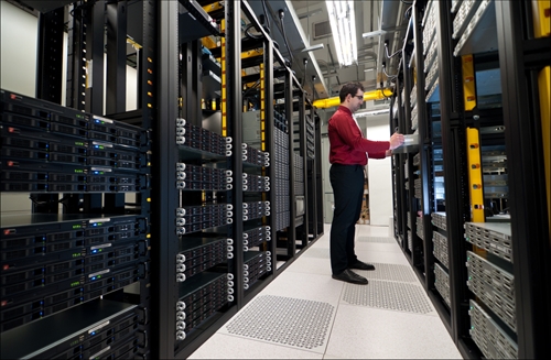 worker moving server onto shelf in server room