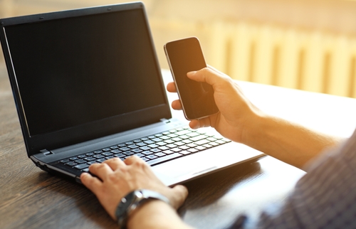 laptop user with mobile phone