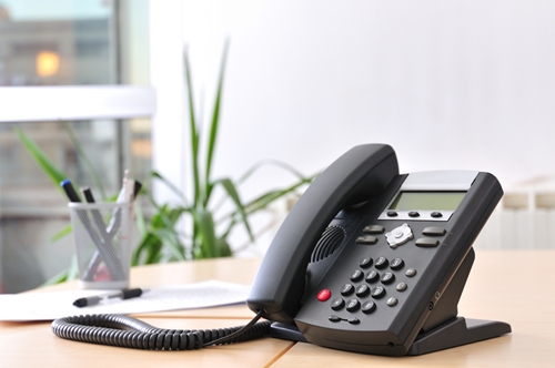 telephone on a desk with pens and plant in the background