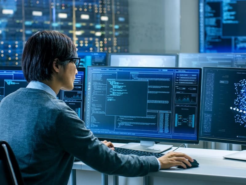 user on a pc looking at code on dual monitors