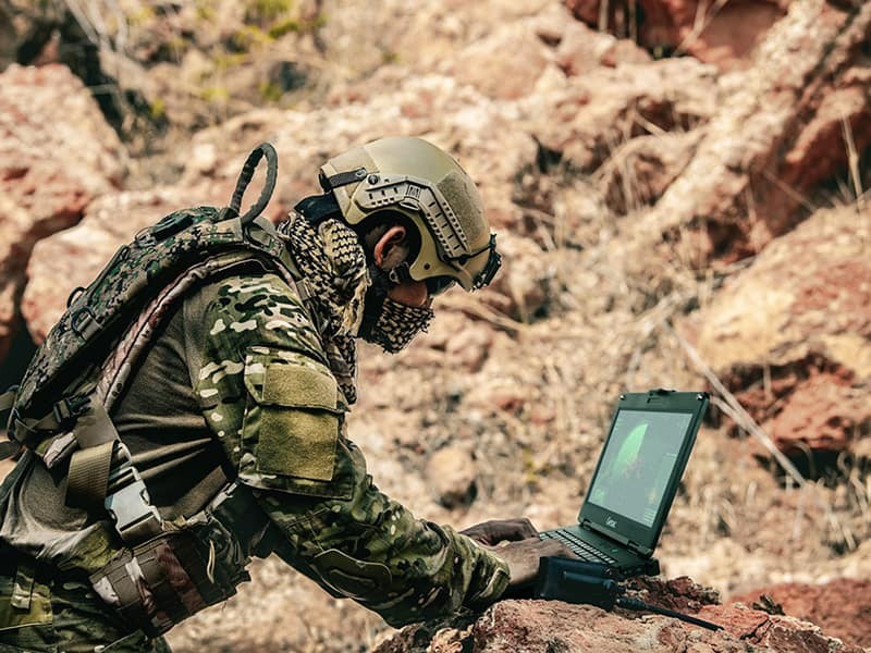 soldier using latop and radio for communication during military operation