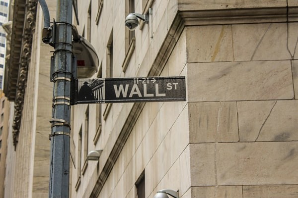 photo of wall street street sign beside traffic lights showing red and building in the background