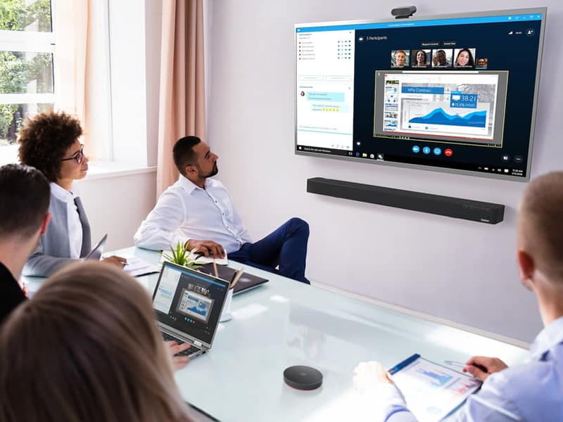 People on a video call in a meeting room looking at a tv on the wall