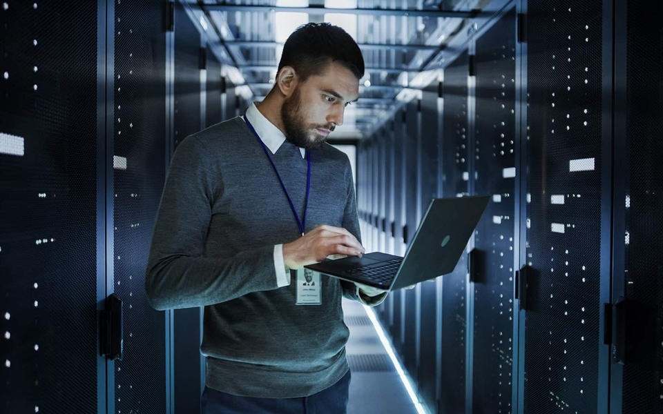 business man with laptop working in a server room